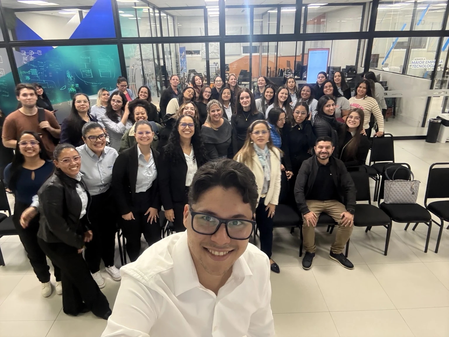 Augusto sorrindo com um grande grupo de profissionais após uma apresentação